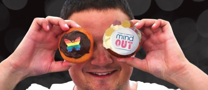 MindOut service user holds cupcakes up to their face