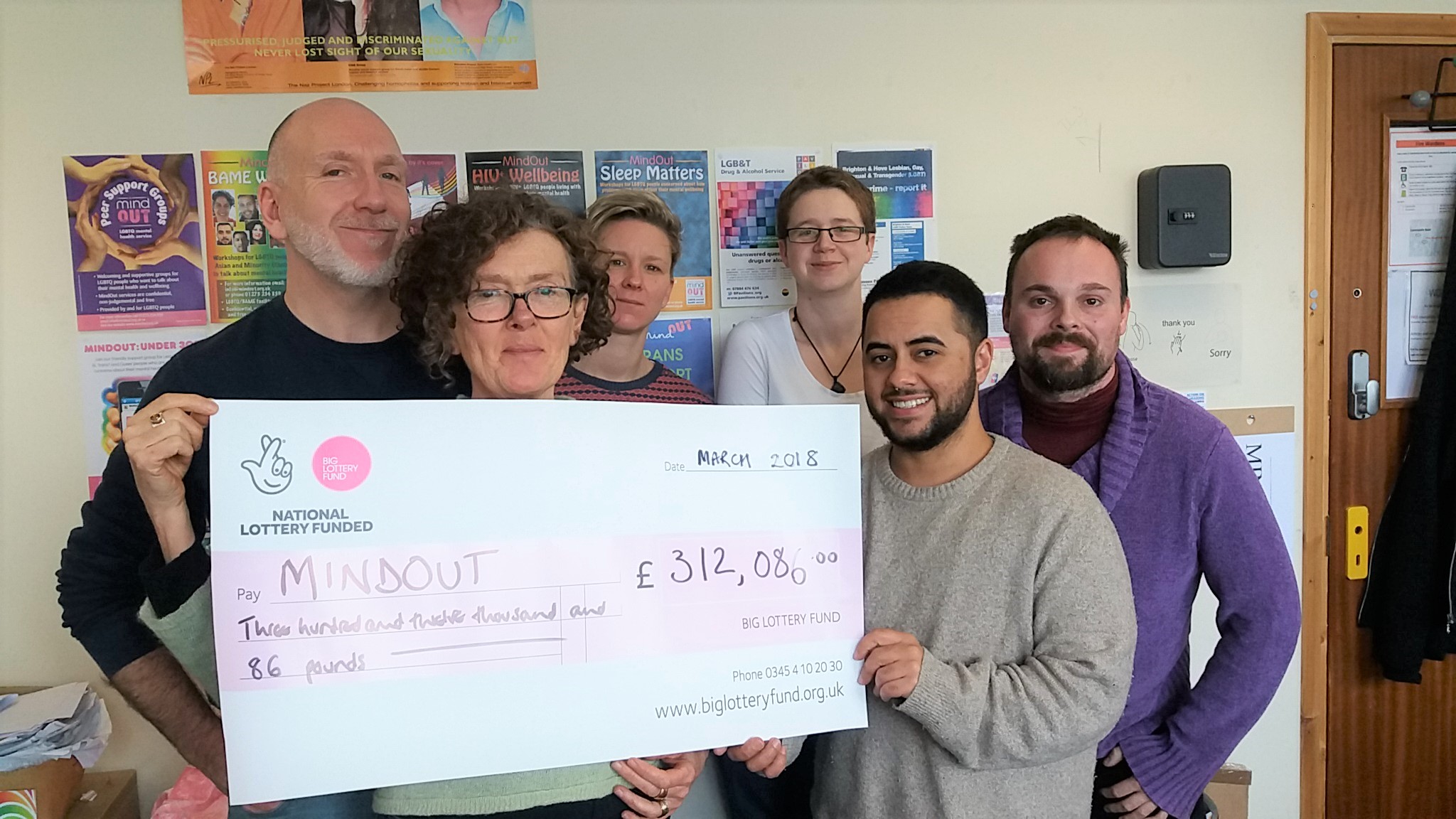 staff at mindout hold a big cheque of their new funding