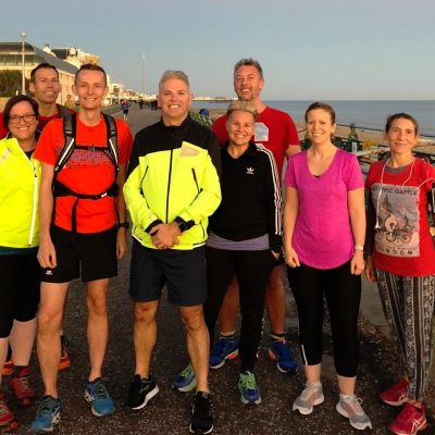 eight people in running gear standing and smiling on brighton beach