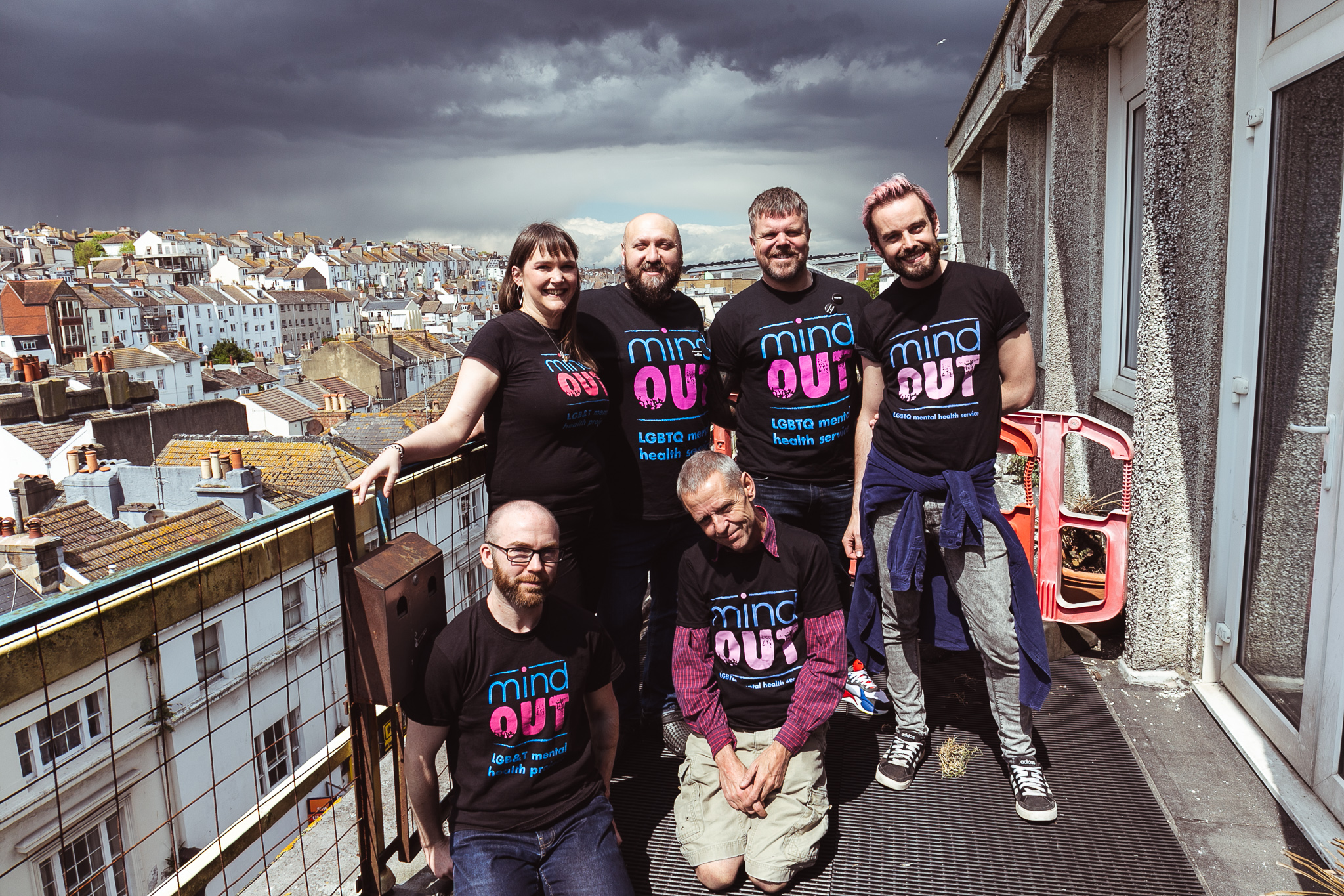 ex mindout volunteers stand on a balcony with dramatic clouds in the background