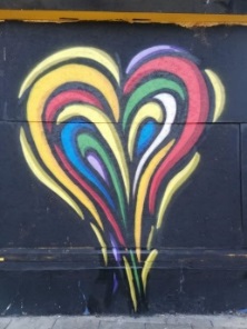 graffiti of heart in rainbow colours on a black wall