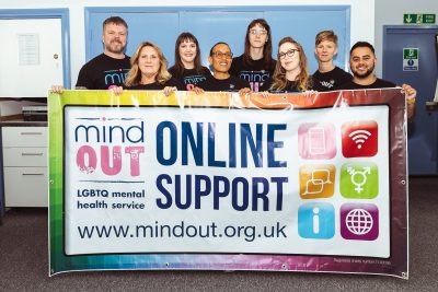 mindout staff holding a large colourful banner for the online support service
