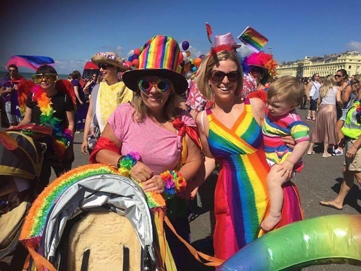 dawn rosie and ella ray at pride wearing colourful rainbow decorations and lots of people in the background