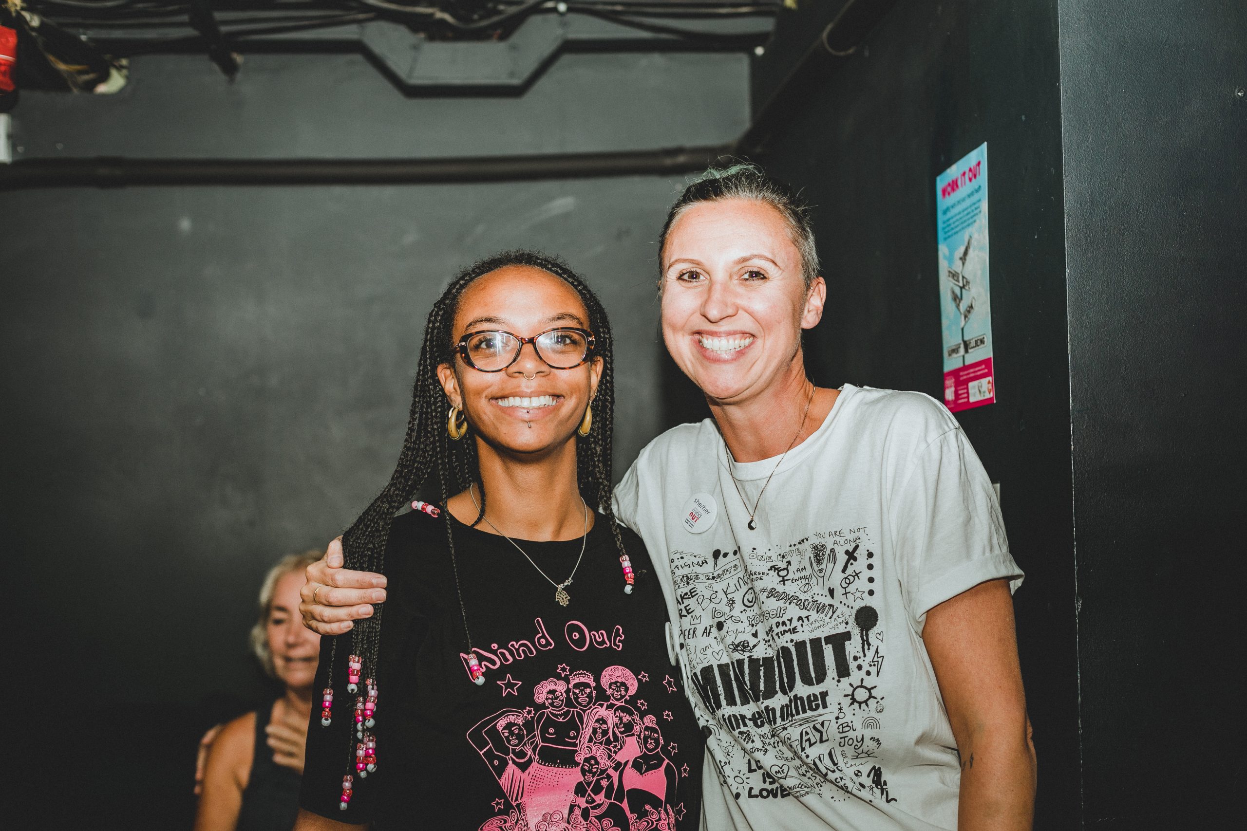 Malaika and Lucy (MindOut staff) smiling together. Both wearing MindOut merch