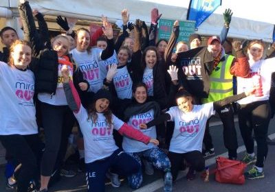 A group of people with their hands in the air, all wearing MindOut t-shirts.