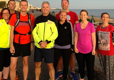eight people in running gear standing and smiling on brighton beach