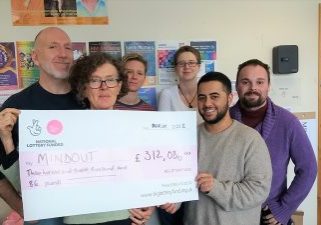 staff at mindout hold a big cheque of their new funding
