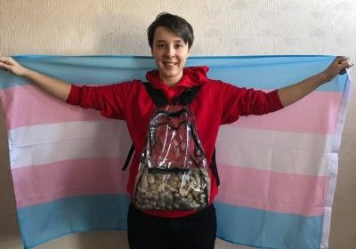eric banks holding a trans flag and a backpack of rocks