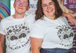 Kip and Gabi (MindOut staff) smiling into the camera wearing the new MindOut merch designed by Fox Fisher